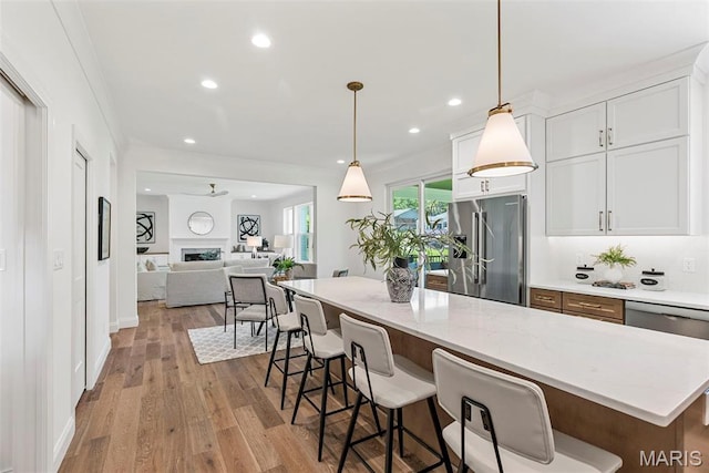 kitchen featuring high end fridge, wood finished floors, white cabinets, recessed lighting, and light stone countertops