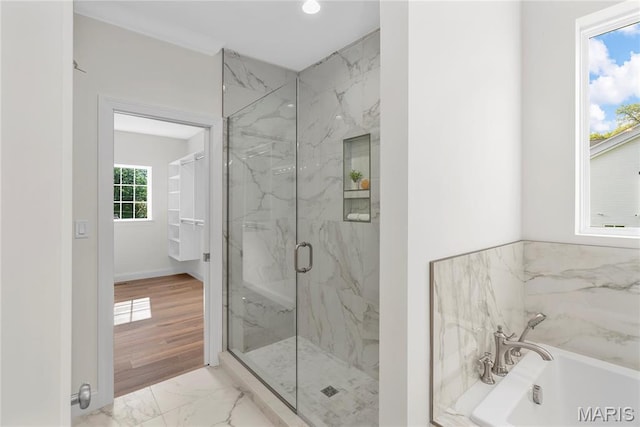 full bath featuring marble look tile flooring, a tub to relax in, a marble finish shower, and baseboards