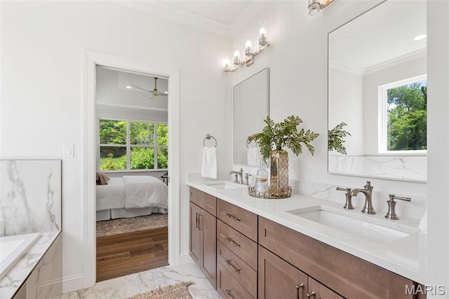 ensuite bathroom featuring marble look tile flooring, ornamental molding, double vanity, ceiling fan, and a tub to relax in
