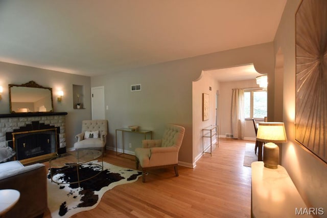 living room featuring light wood-style flooring, a fireplace, and baseboards
