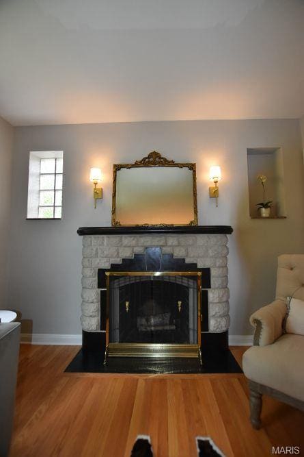 detailed view of a fireplace, baseboards, and wood finished floors