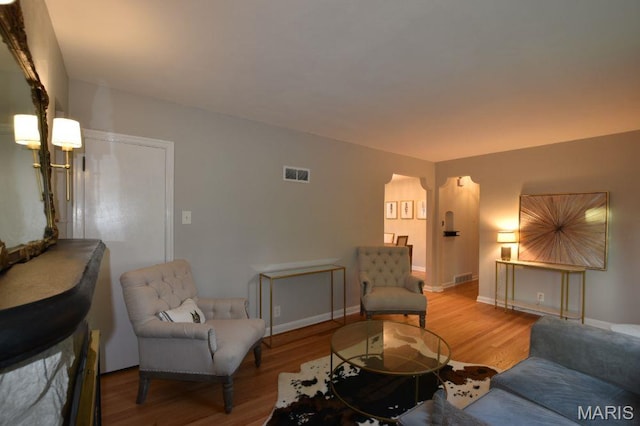 living room with wood finished floors, baseboards, and arched walkways