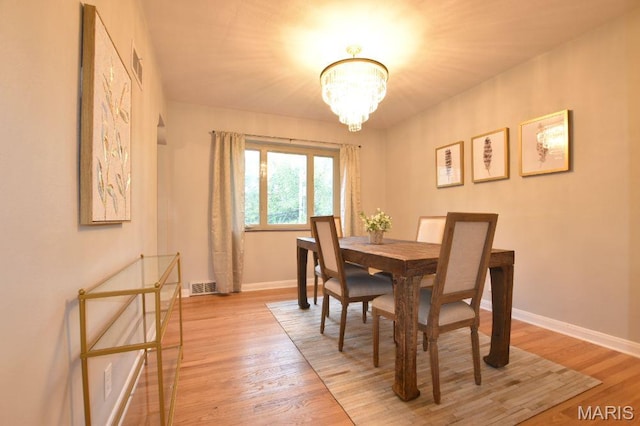 dining room featuring a chandelier, baseboards, and light wood-style floors
