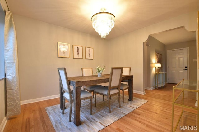 dining room featuring a chandelier, wood finished floors, and baseboards