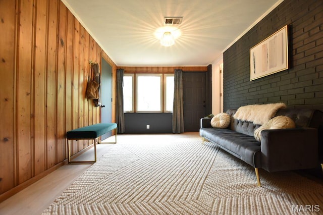 living area featuring wood walls, ornamental molding, and baseboards