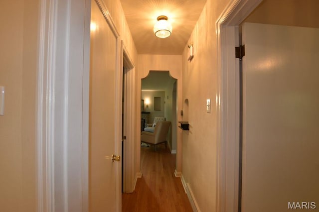 corridor featuring wood finished floors and baseboards