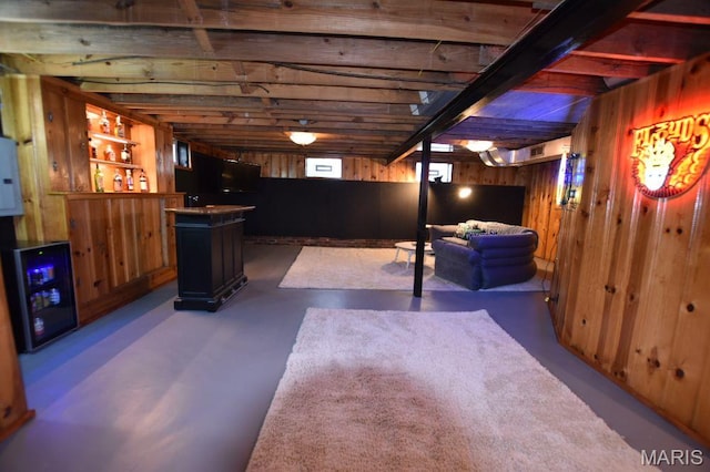 below grade area featuring wood walls, a dry bar, and beverage cooler