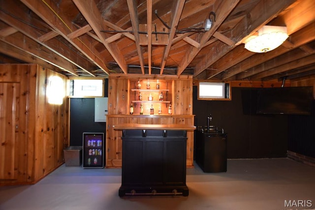 basement featuring wine cooler, wood walls, and a bar