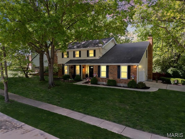view of front of home featuring brick siding, a chimney, a lawn, and a garage