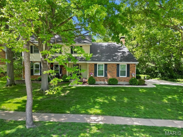 view of front facade with a front yard, brick siding, and a chimney