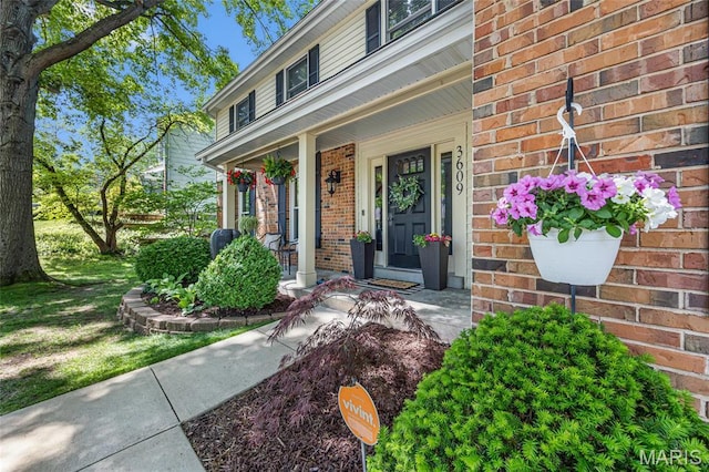 property entrance with a porch and brick siding