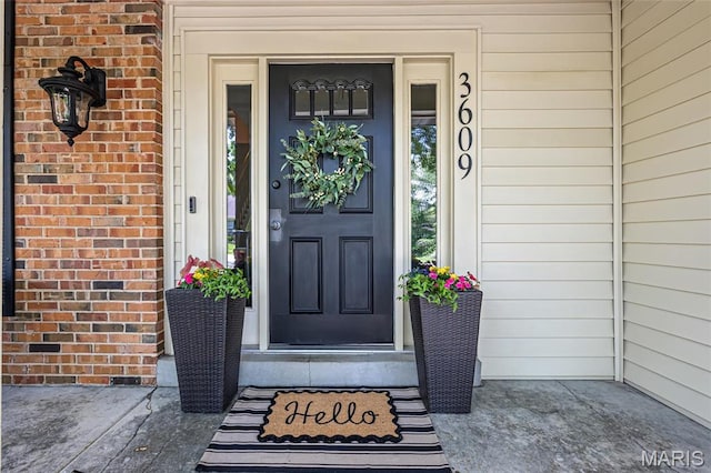 view of exterior entry featuring brick siding and a porch