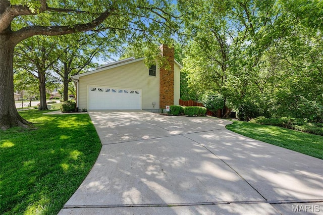 view of side of property with concrete driveway, a chimney, and an attached garage