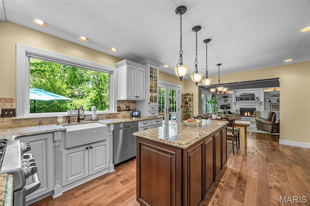 kitchen with stainless steel appliances, a sink, light wood finished floors, white cabinets, and decorative backsplash