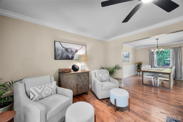 sitting room featuring wood finished floors, crown molding, ceiling fan, a chandelier, and baseboards