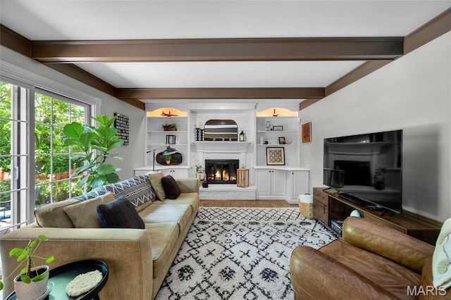 living room with a fireplace, beam ceiling, and light wood-style flooring