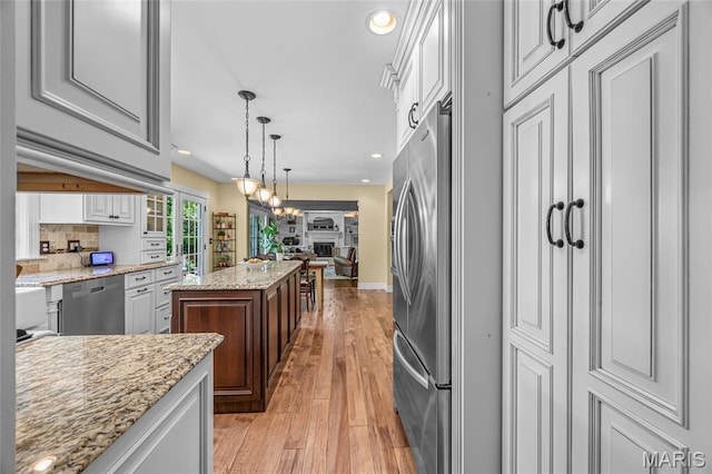 kitchen featuring appliances with stainless steel finishes, light wood finished floors, white cabinetry, hanging light fixtures, and recessed lighting