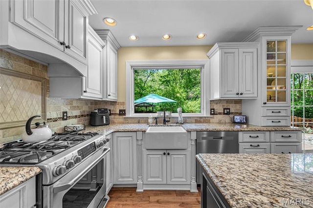 kitchen with stainless steel appliances, a sink, white cabinets, glass insert cabinets, and recessed lighting