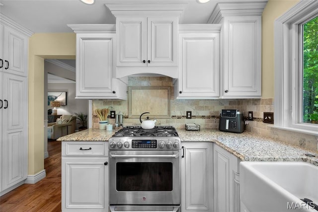 kitchen with gas stove, white cabinetry, and tasteful backsplash