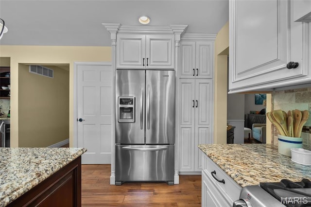 kitchen featuring stainless steel fridge with ice dispenser, dark wood finished floors, light stone countertops, white cabinetry, and backsplash