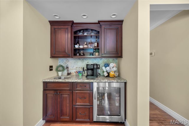 indoor bar featuring beverage cooler, decorative backsplash, baseboards, and wood finished floors