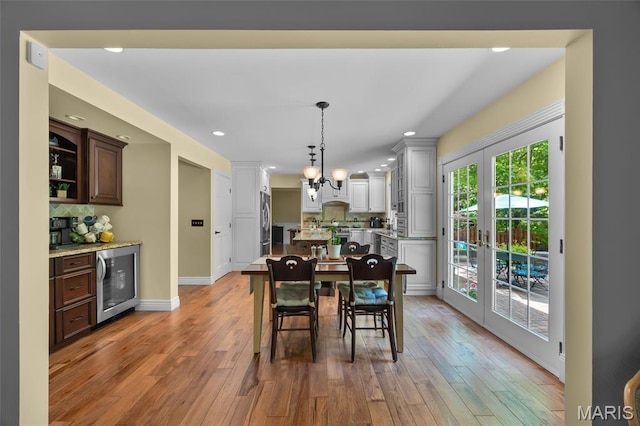 dining area with wine cooler, a chandelier, light wood finished floors, recessed lighting, and french doors