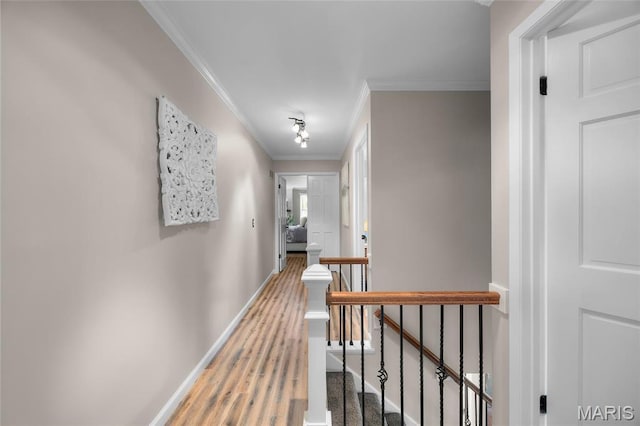 hallway featuring an upstairs landing, ornamental molding, baseboards, and wood finished floors
