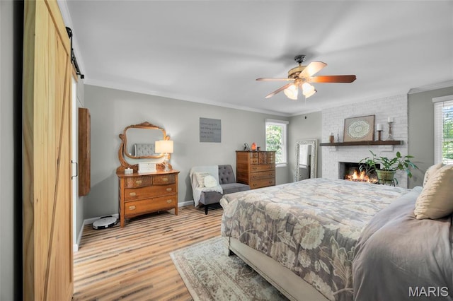 bedroom with crown molding, light wood-type flooring, baseboards, a brick fireplace, and a ceiling fan