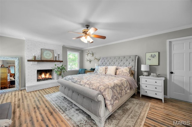 bedroom featuring ornamental molding, wood finished floors, a fireplace, and ceiling fan
