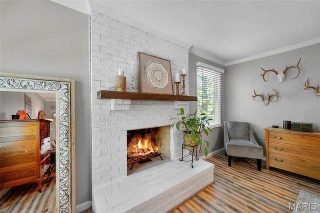 sitting room featuring crown molding, wood finished floors, baseboards, and a brick fireplace