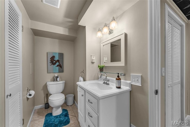 half bathroom featuring a closet, toilet, vanity, tile patterned floors, and baseboards