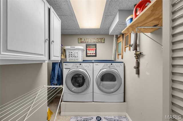 laundry area featuring separate washer and dryer, cabinet space, baseboards, and tile patterned flooring