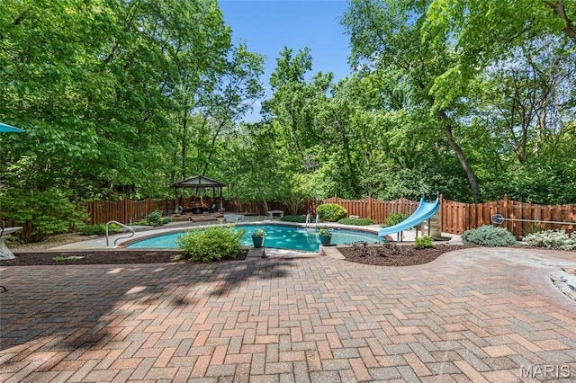 view of pool with a gazebo, a water slide, a patio, and a fenced backyard
