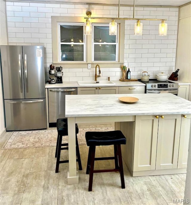 504 Henrietta St, Gillespie, IL 62033 - kitchen with stainless steel appliances, a sink, decorative backsplash, hanging light fixtures, and light wood-style floors