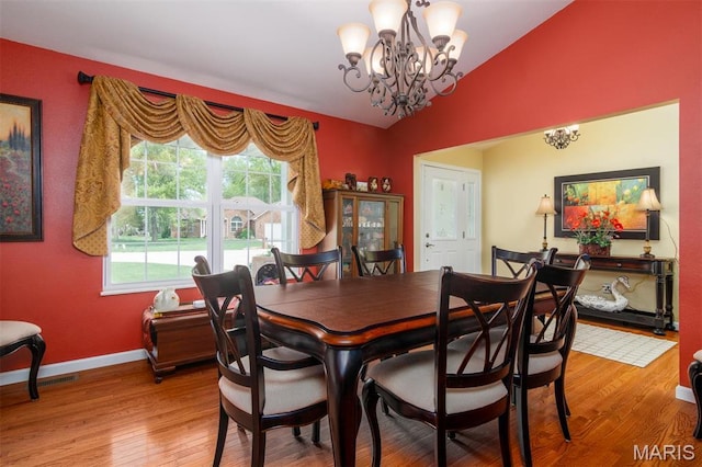 9574 Woodcrest Pl, Breese, IL 62230 - dining space featuring vaulted ceiling, a chandelier, light wood-style flooring, and baseboards