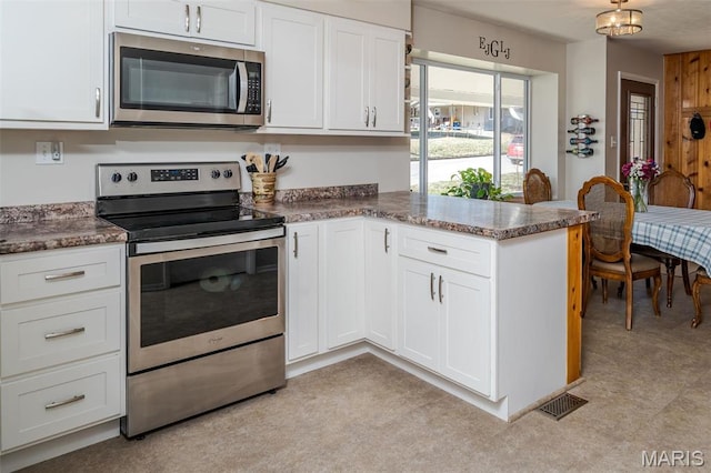 729 W State St, Union, MO 63084 - kitchen with appliances with stainless steel finishes, white cabinets, a peninsula, and dark stone countertops