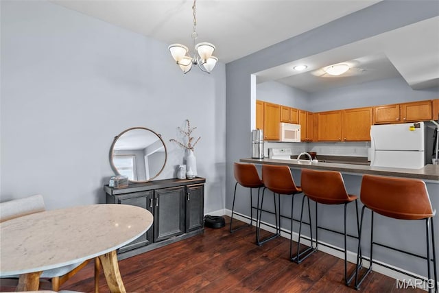 1239 Gardens Circle Dr Unit I, Saint Louis, MO 63125 - kitchen with white appliances, a breakfast bar area, a chandelier, dark wood-type flooring, and backsplash