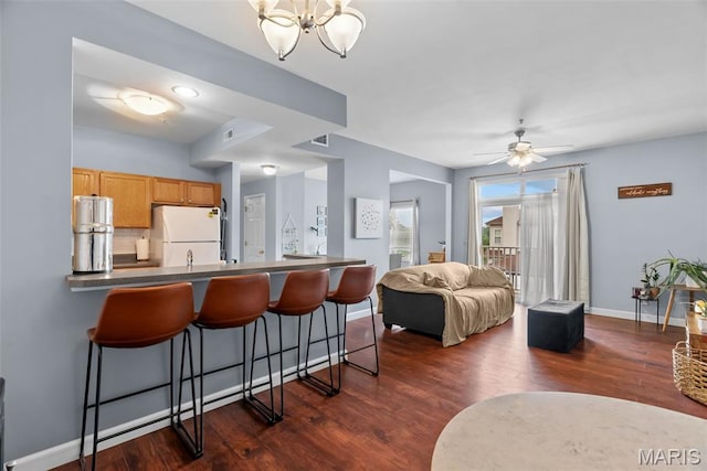 1239 Gardens Circle Dr Unit I, Saint Louis, MO 63125 - kitchen with freestanding refrigerator, dark countertops, a kitchen bar, and dark wood-style floors