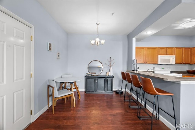 1239 Gardens Circle Dr Unit I, Saint Louis, MO 63125 - kitchen featuring white appliances, a breakfast bar, dark wood finished floors, baseboards, and a chandelier