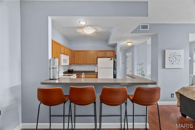 1239 Gardens Circle Dr Unit I, Saint Louis, MO 63125 - kitchen with white appliances, dark countertops, a peninsula, and a breakfast bar area