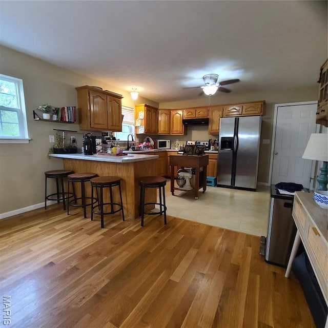 8 Nathan St, Waynesville, MO 65583 - kitchen with stainless steel appliances, a peninsula, a sink, under cabinet range hood, and brown cabinetry