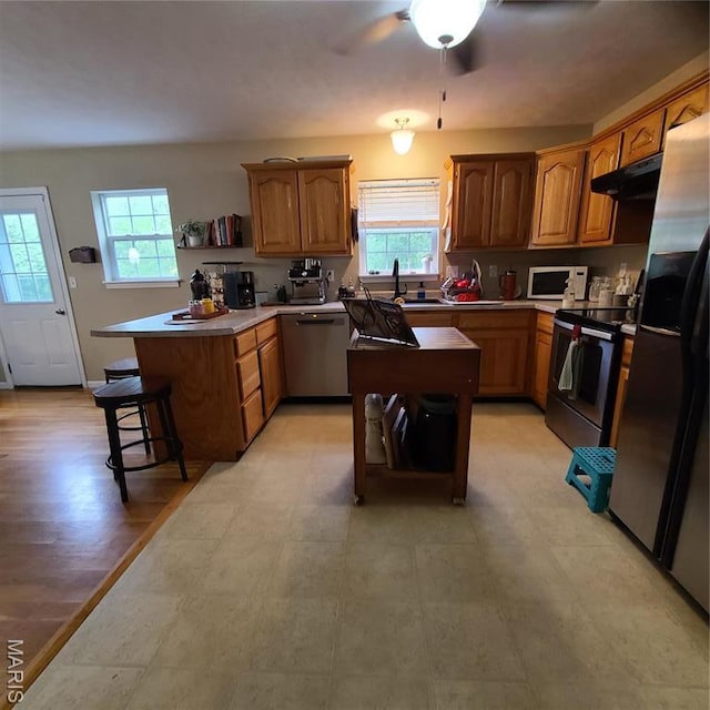 8 Nathan St, Waynesville, MO 65583 - kitchen with stainless steel appliances, under cabinet range hood, a peninsula, and plenty of natural light