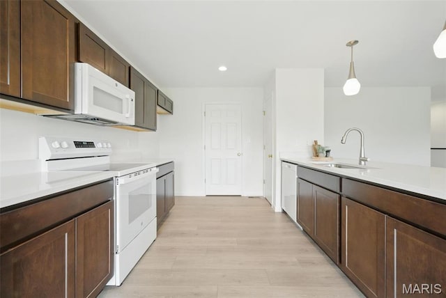 114 Harrow Dr, Ofallon, MO 63385 - kitchen featuring white appliances, a sink, light countertops, light wood-style flooring, and hanging light fixtures