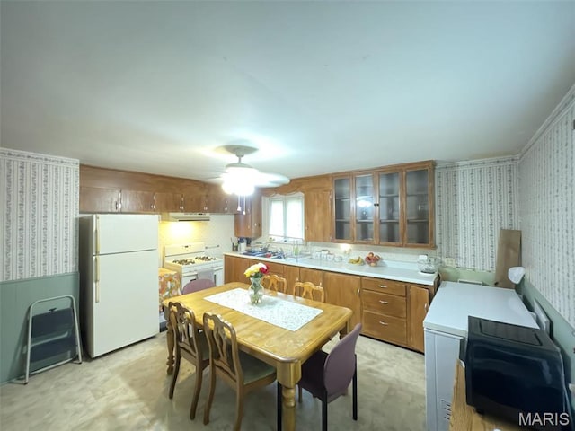 308 S Cedar St, Trenton, IL 62293 - kitchen with white appliances, wallpapered walls, brown cabinetry, a ceiling fan, and glass insert cabinets