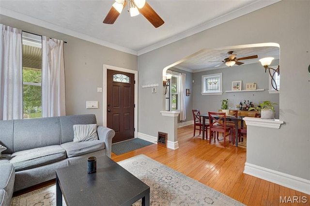 5245 Robert Ave, Saint Louis, MO 63109 - living area featuring ceiling fan, baseboards, arched walkways, light wood-style flooring, and crown molding