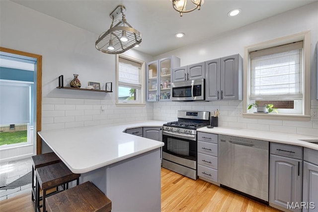 5245 Robert Ave, Saint Louis, MO 63109 - kitchen with stainless steel appliances, gray cabinets, a breakfast bar, a peninsula, and recessed lighting