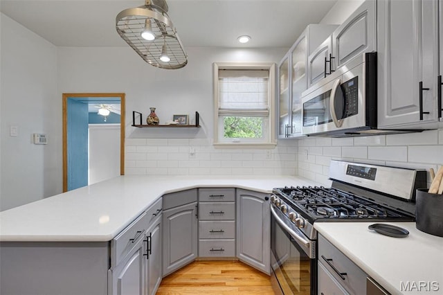 5245 Robert Ave, Saint Louis, MO 63109 - kitchen with appliances with stainless steel finishes, gray cabinetry, a peninsula, decorative backsplash, and light countertops