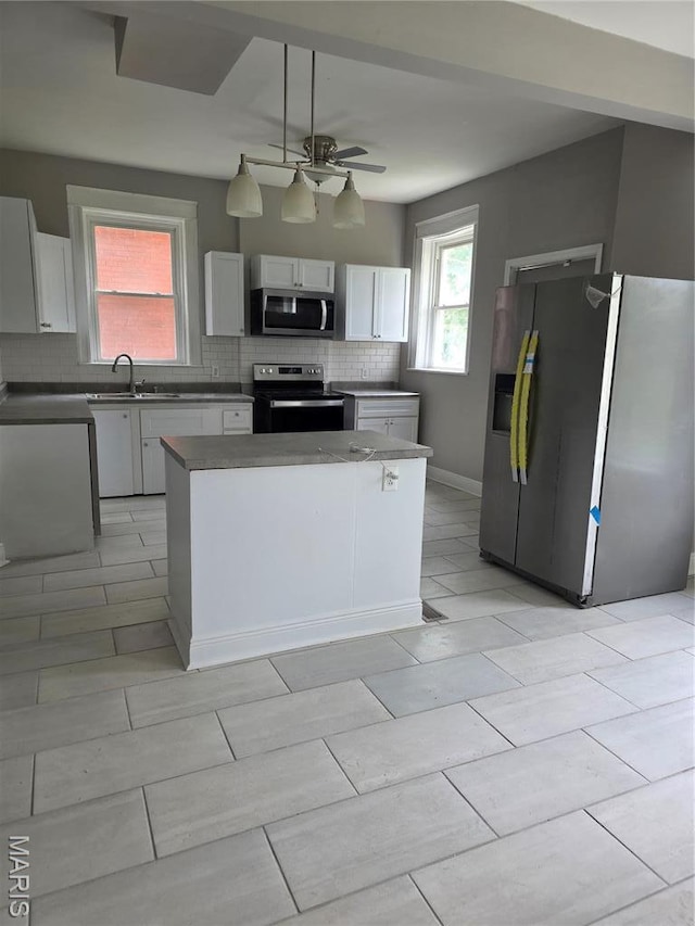 5614 Etzel Ave, Saint Louis, MO 63112 - kitchen featuring appliances with stainless steel finishes, a sink, tasteful backsplash, and white cabinetry
