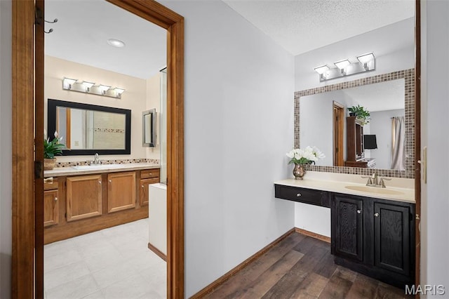 108 Antoinette Ter, Lake St Louis, MO 63367 - bathroom featuring decorative backsplash, two vanities, baseboards, and wood finished floors