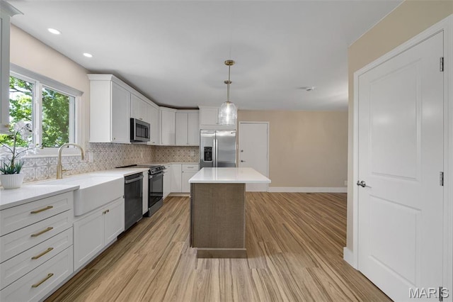 1200 Auber Dr, Manchester, MO 63011 - kitchen featuring appliances with stainless steel finishes, a sink, decorative backsplash, light wood finished floors, and white cabinets